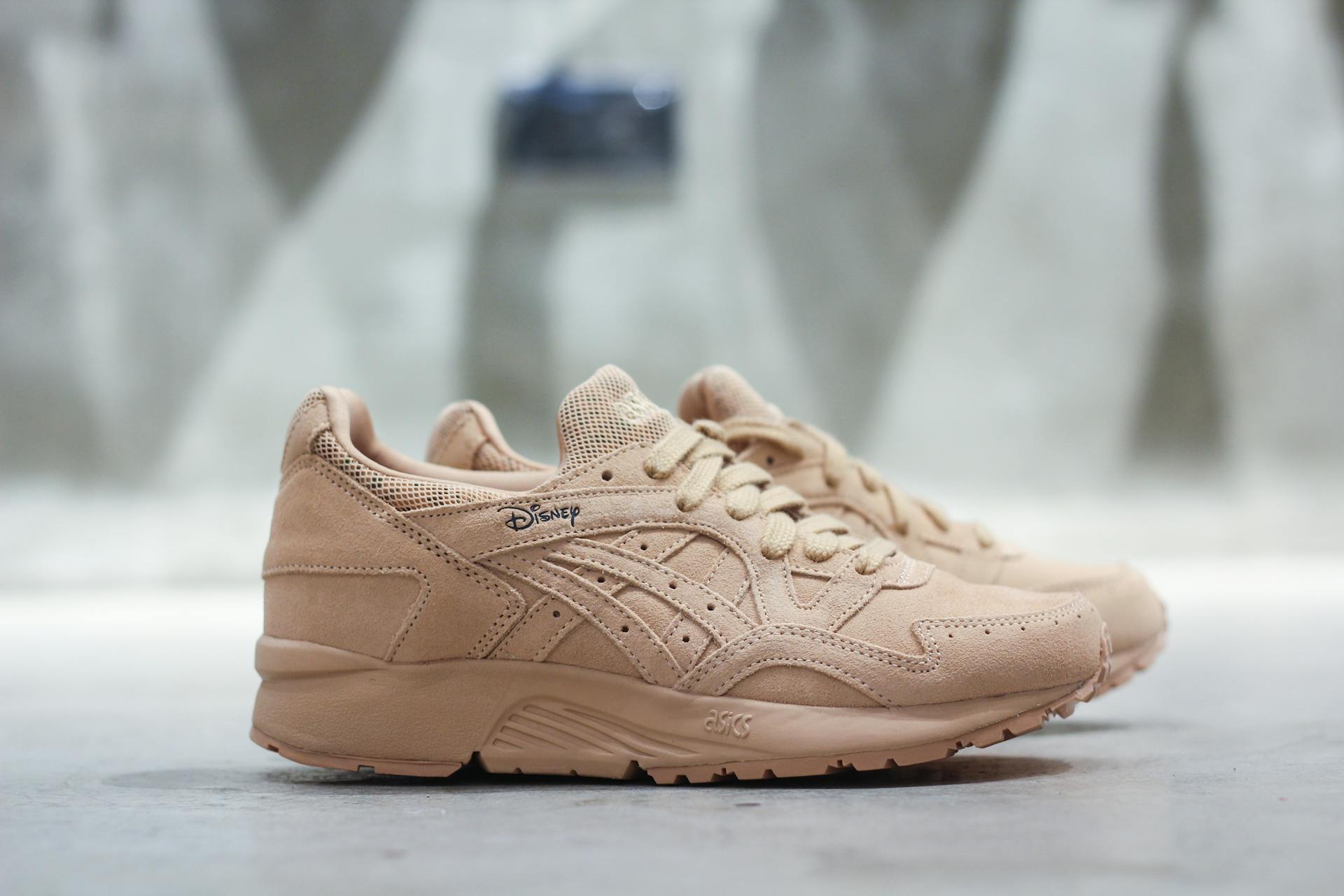 Close-up of limited edition beige Asics sneakers on a concrete background, showcasing modern style.