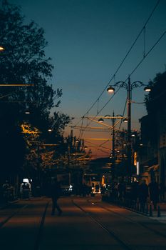 Street scene in Istanbul with silhouettes of people walking under illuminated street lights at dusk.