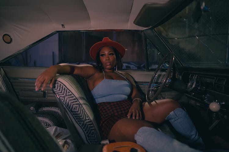 Dark Photo Of A Woman Wearing Red Hat Sitting In A Vintage Car