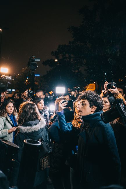 Fotomural Una multitud diversa en un evento nocturno en Estambul, iluminada por luces de cámaras y teléfonos.