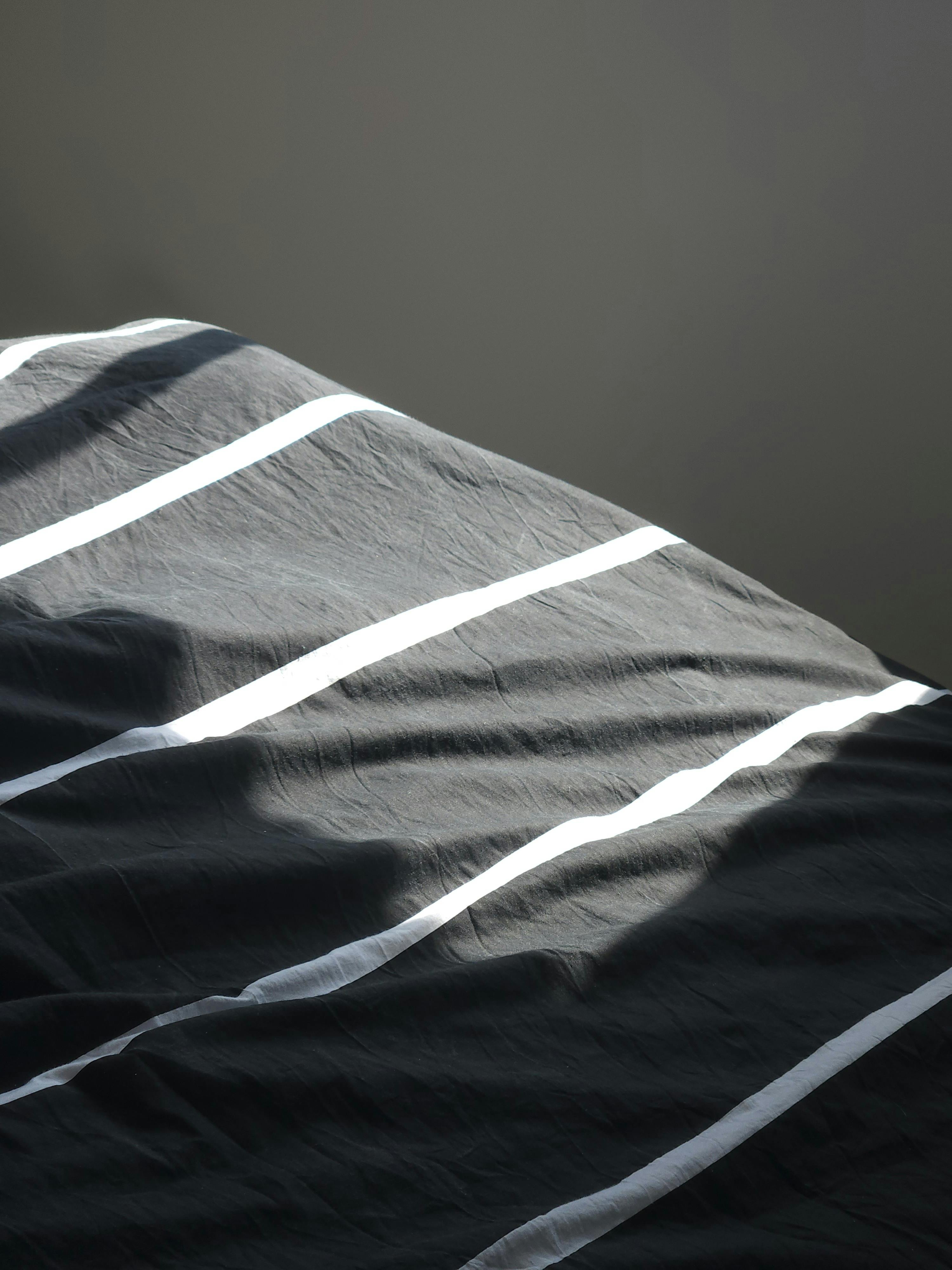 a close view of striped sheets wrinkled by sunlight on a lived-in bed