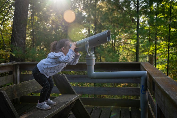 Little Girl Looking Through A Telescope