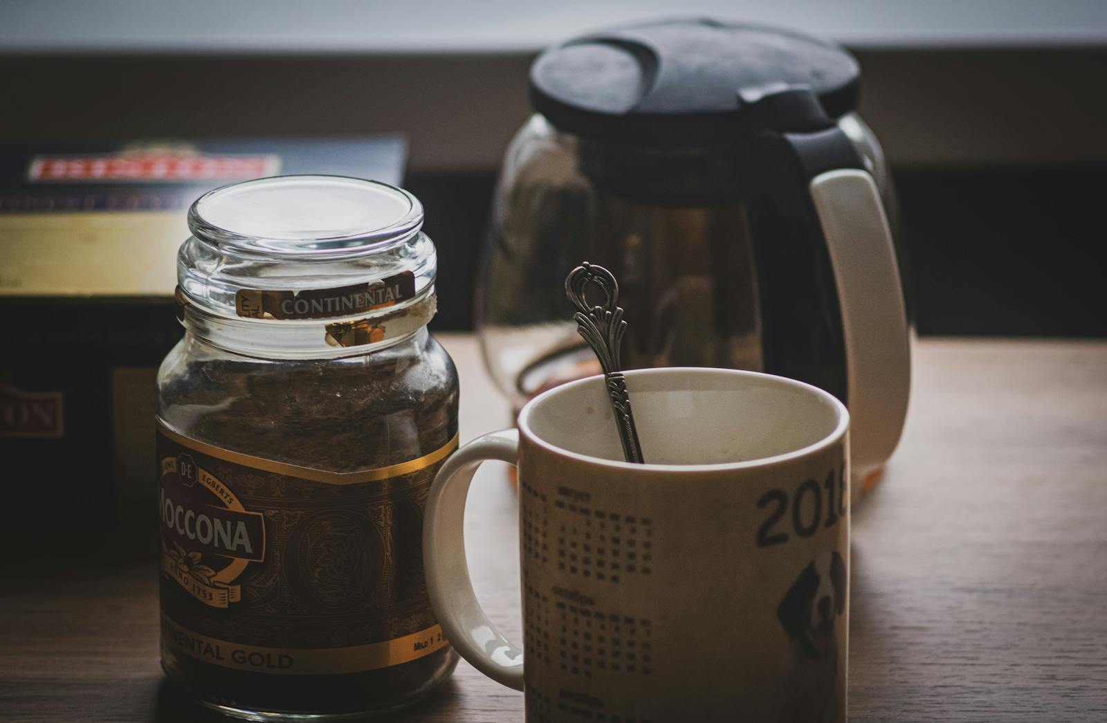 Instant coffee jar beside a mug on a wooden table