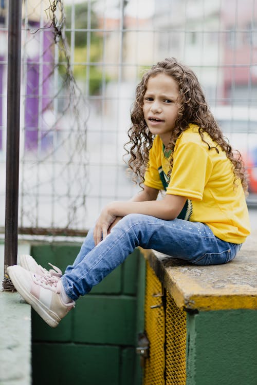 Young Girl in Yellow Shirt Sitting on a Platform