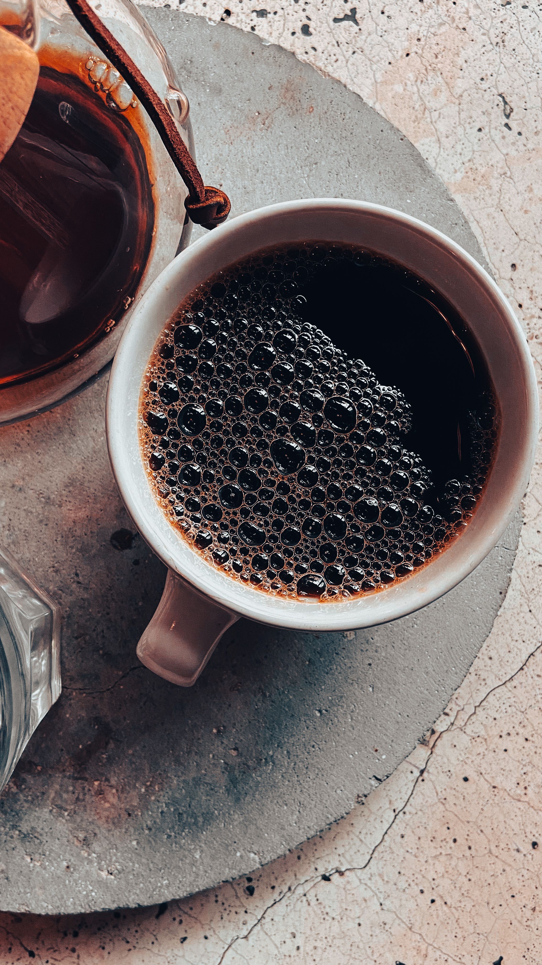 A bag of coffee and a ceramic cup on a sunlit table
