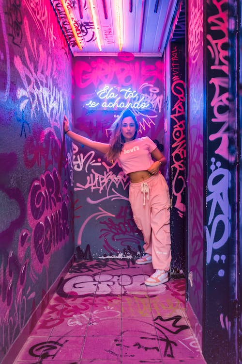 Woman in Pink Tracksuit Standing Among Wall Murals 