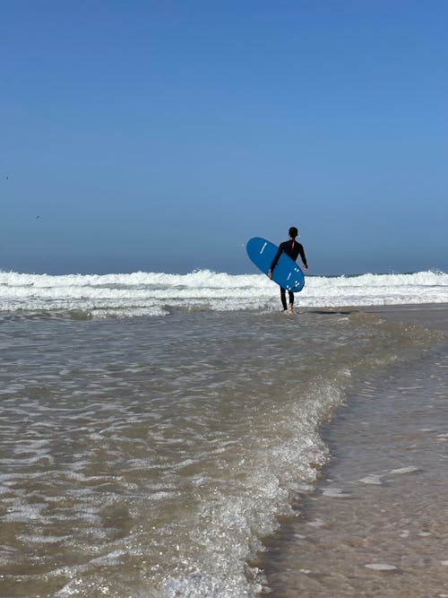 Free Surfer Walking on Shallow Water Stock Photo