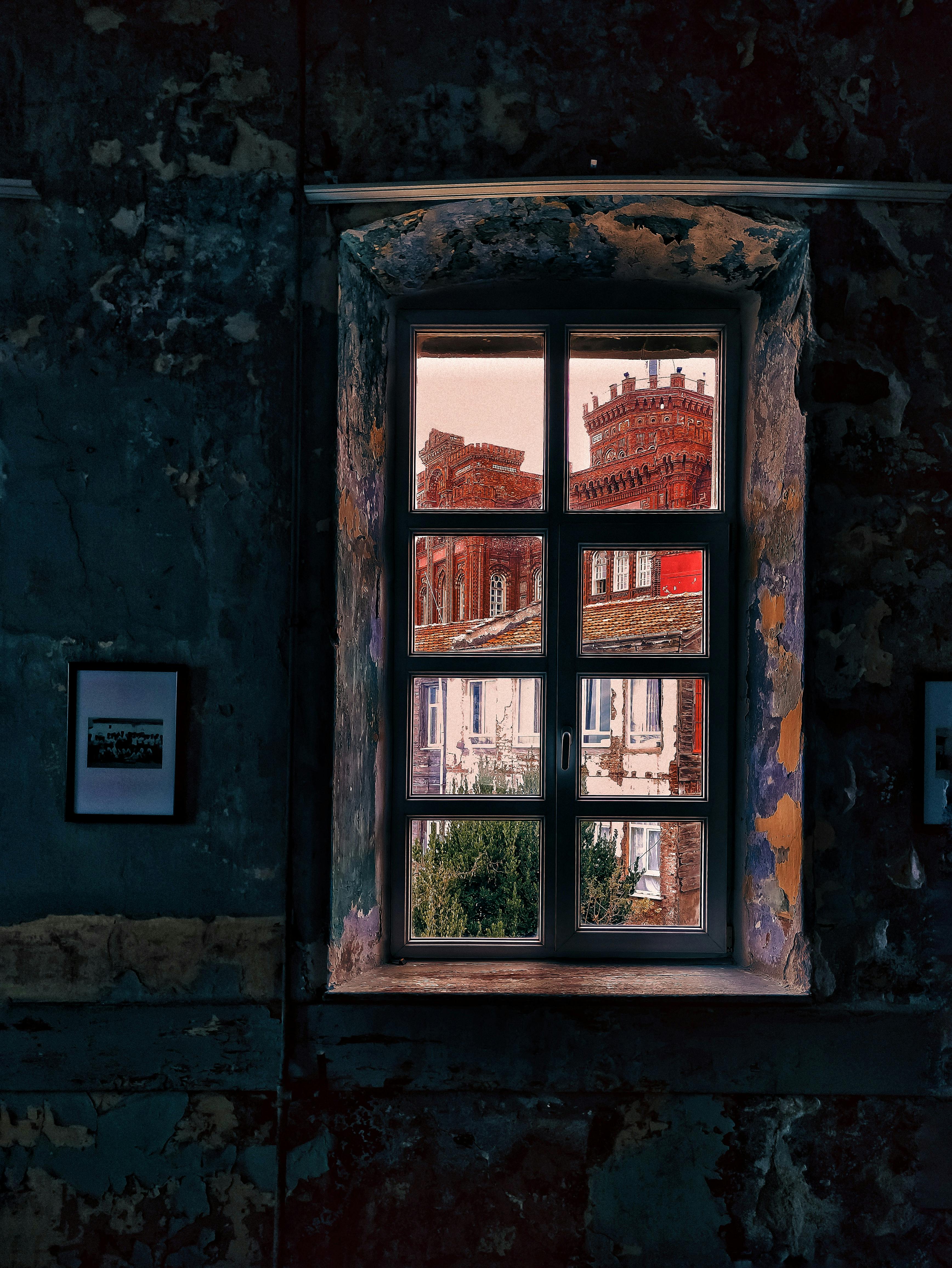 A historic building seen through an aged window frame, capturing urban decay.
