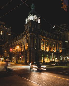 Night scene of the illuminated facade of Sinclair Centre in Vancouver with city lights and traffic.