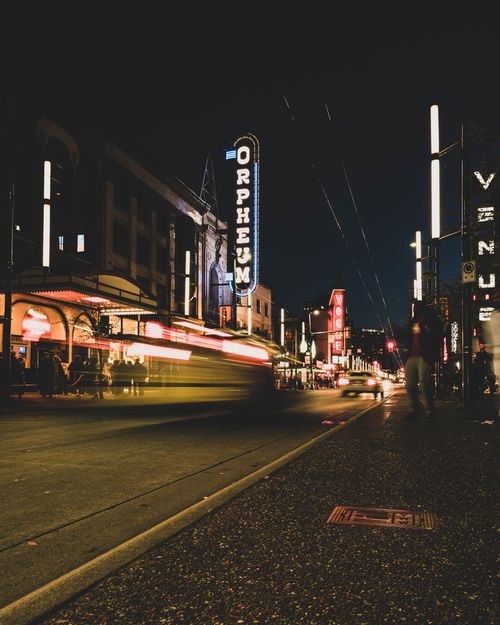 Free Vibrant city nightlife with illuminated neon signs and motion blur of traffic on Orpheum Street. Stock Photo