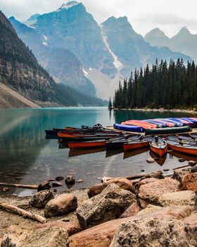 Canoes docked by the tranquil waters of Moraine Lake surrounded by majestic mountains.