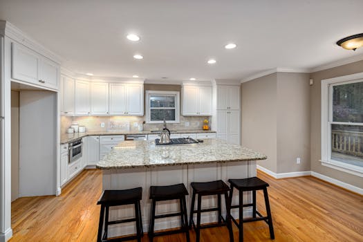 Spacious modern kitchen featuring a granite island and white cabinets.