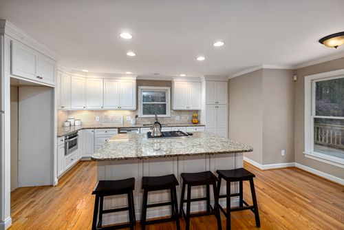Free Spacious modern kitchen featuring a granite island and white cabinets. Stock Photo