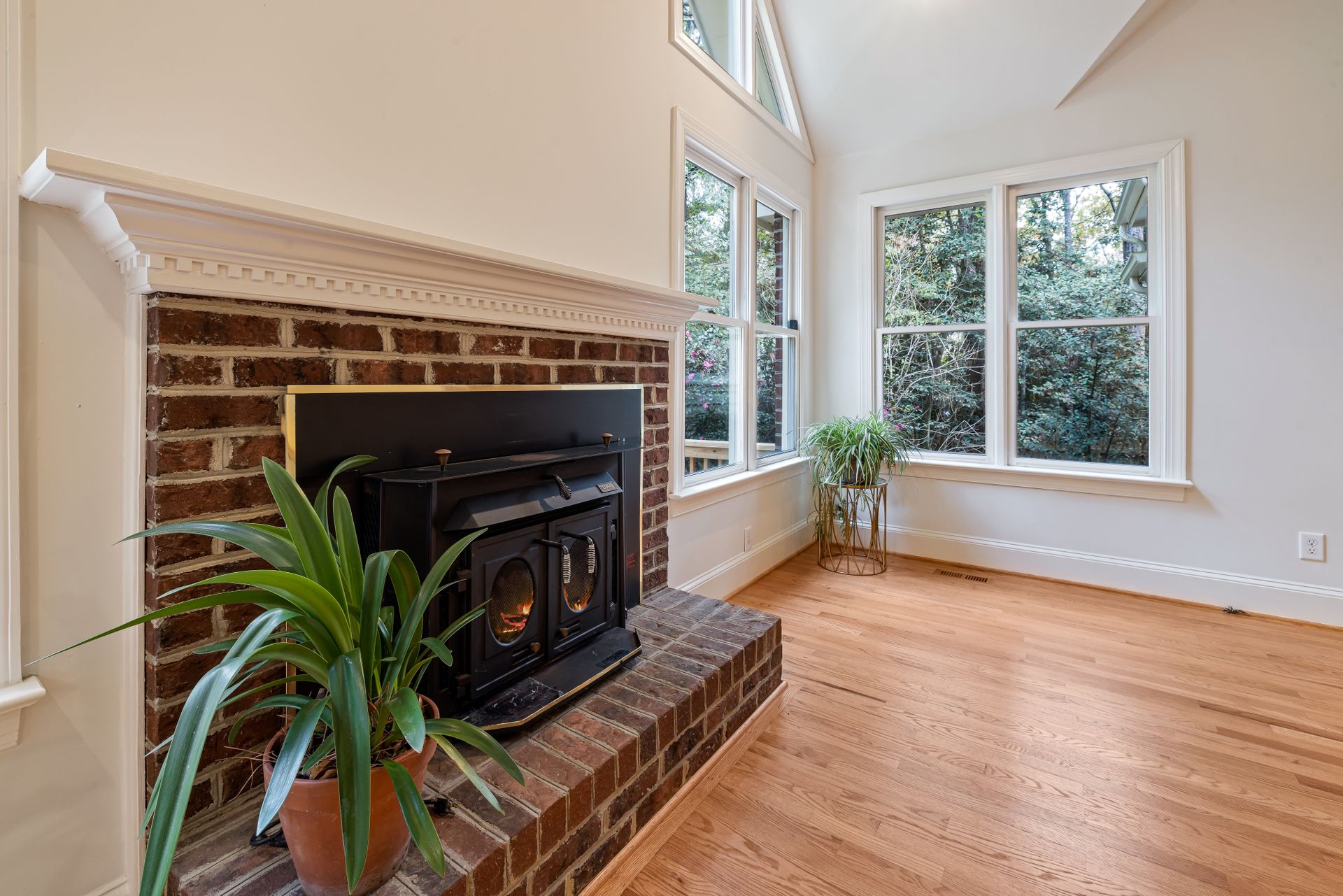 Inviting living room interior with a brick fireplace and large windows inviting natural light.