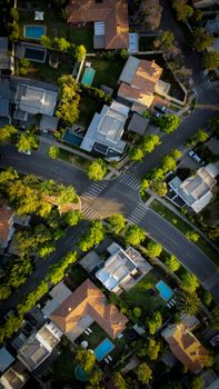 High-angle aerial view of an urban residential neighborhood with intersecting roads and green trees.