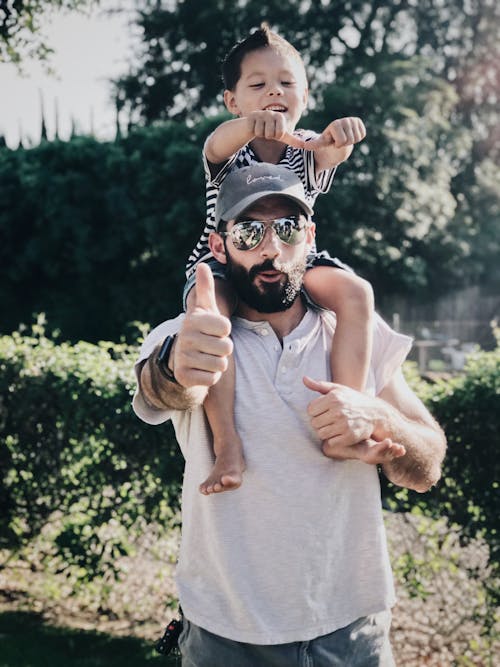 Man in White T-shirt Carrying Boy on His Back