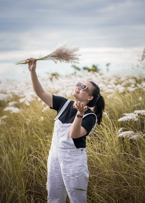 Smiling Woman Holding a Bunch of Grass on a Field 