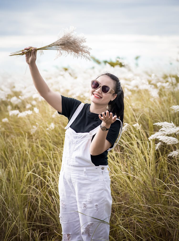 Smiling Woman Holding A Bunch Of Grass On A Field 