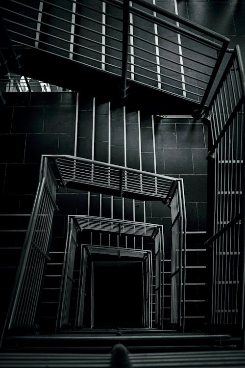 Grayscale Photo of a Building Stairway with Metal Railings