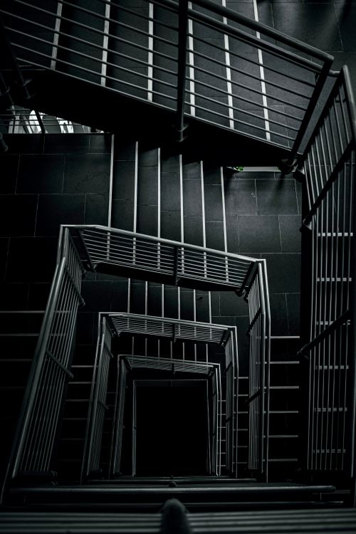 Free Striking black and white view of a staircase with metal railings, creating a dramatic effect. Stock Photo