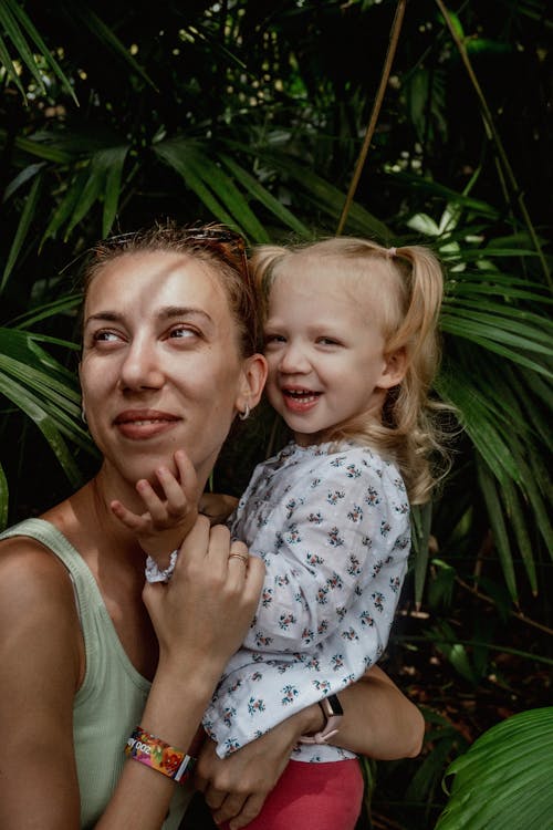 Woman in White Tank Top Carrying Girl in Floral Top