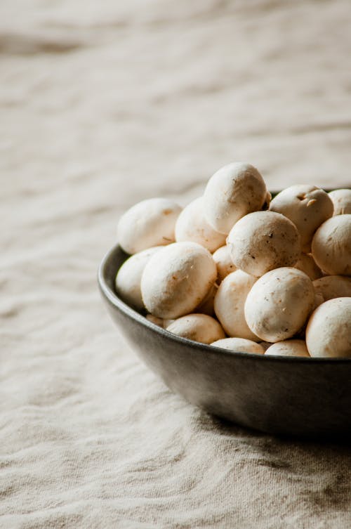 Champignons in a Bowl on a Beige Tablecloth