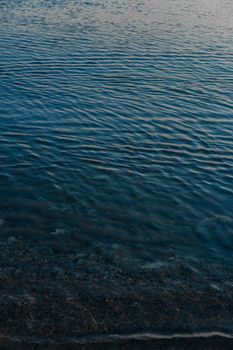 Rippling blue water at the shore creates a tranquil and calming scene during dusk.