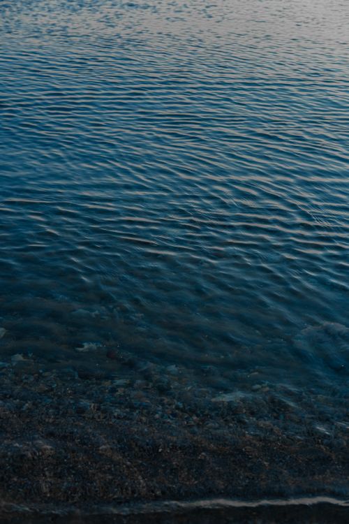 Free Rippling blue water at the shore creates a tranquil and calming scene during dusk. Stock Photo