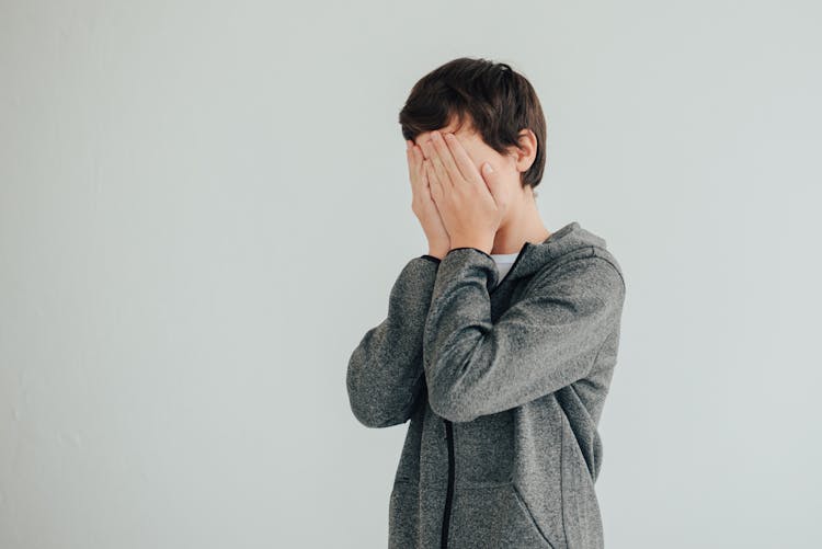 Boy Covering Face In Hands