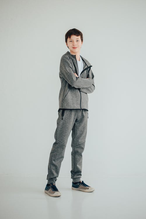 A Young Boy in Gray Jacket and Pants Standing with His Arms Crossed