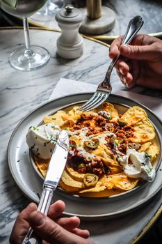 A plate of Mexican nachos topped with minced meat and sour cream, perfect for a snack or meal.