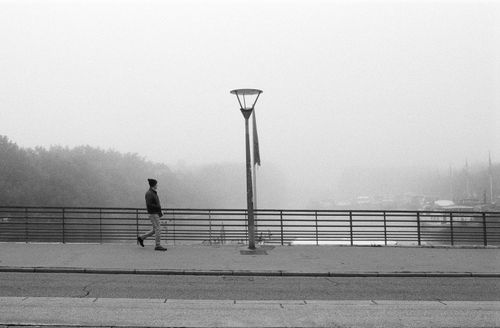 Free Black and white photo of a lone man walking on a foggy street. Stock Photo