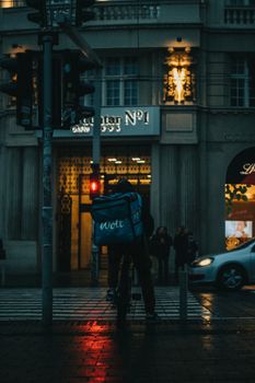 Food delivery cyclist on a rainy evening in Cluj-Napoca, capturing urban life with a moody atmosphere.
