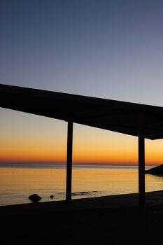 A mesmerizing sunset view over the calm sea at Durrës Beach, Albania, with silhouettes and an orange sky.