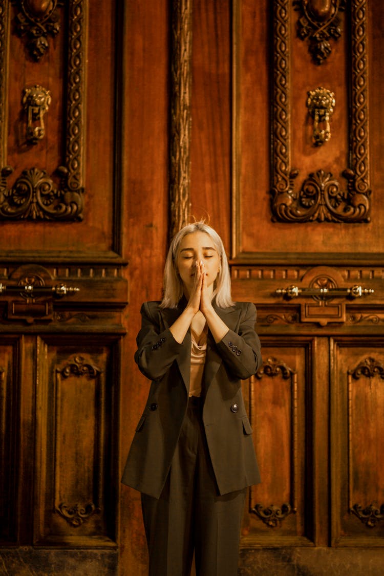 Woman With Prayer Hands On Wooden Door Background