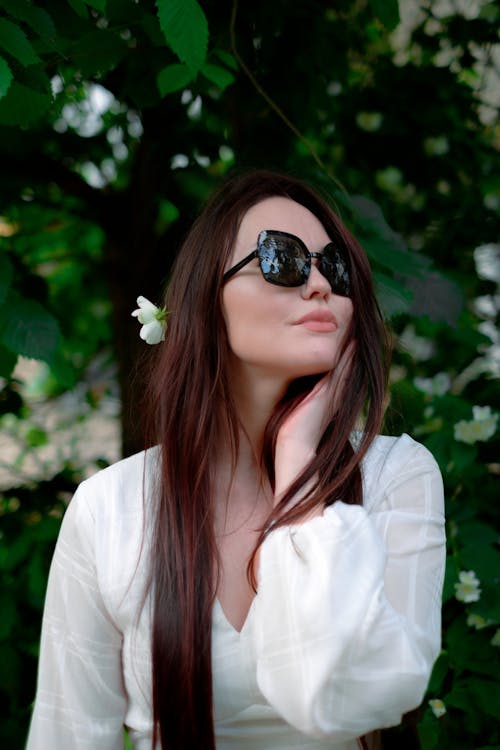 Woman in Sunglasses with a White Flower in Her Hair