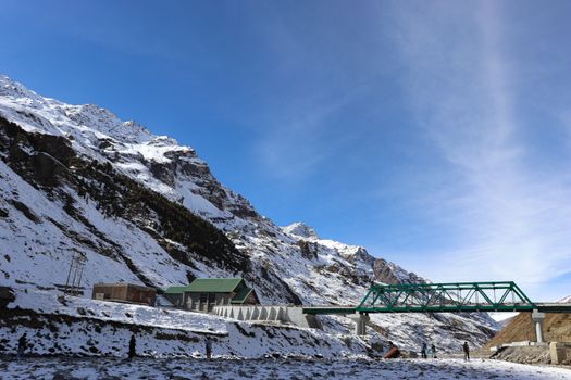 Breathtaking winter view of snowcapped mountains and bridge in Manali, India.
