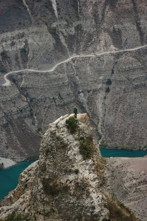 Free Person stands on cliff edge overlooking Sulak Canyon's rugged landscape in Dagestan, Russia. Stock Photo