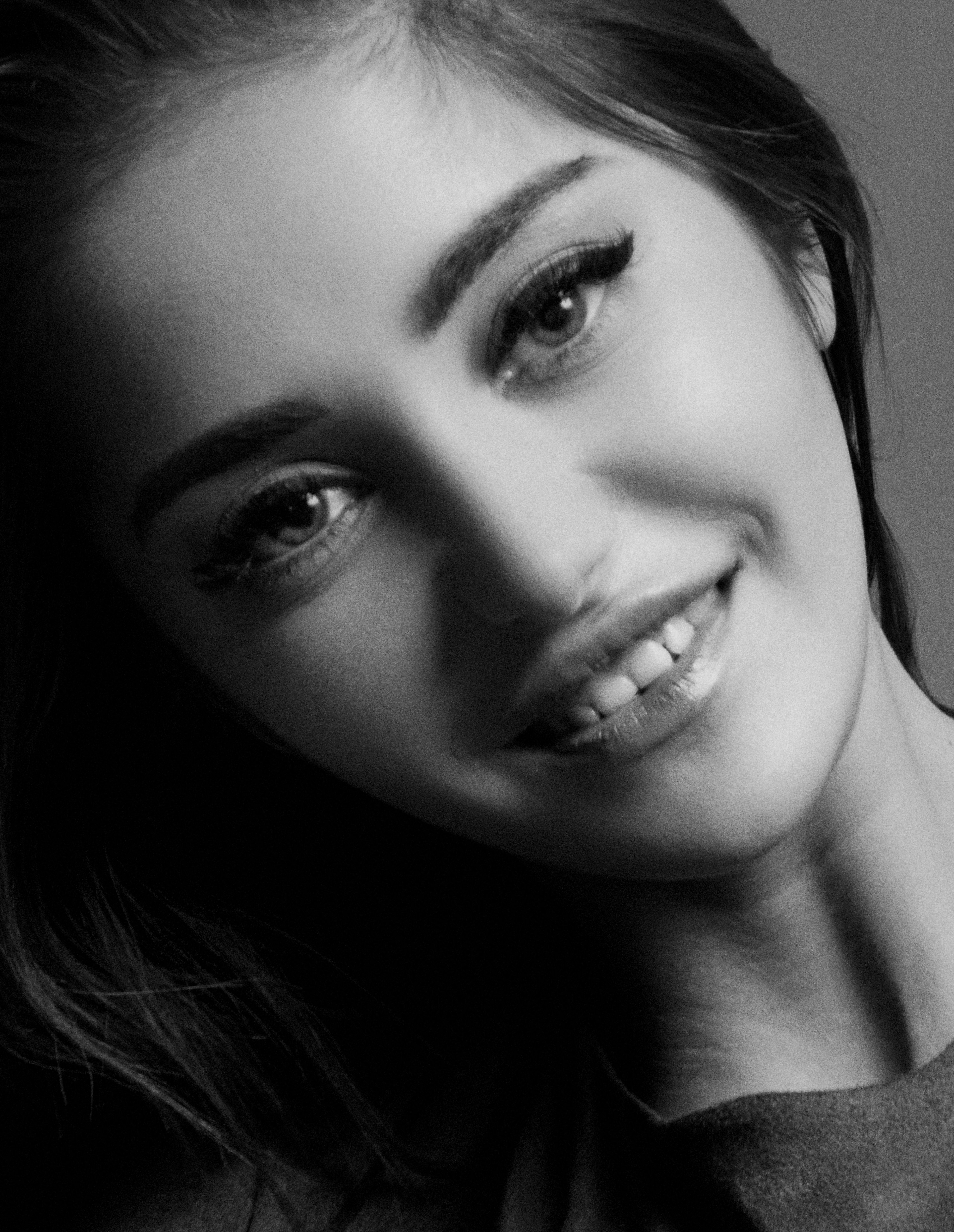 Artistic black and white portrait capturing a woman's smiling expression.