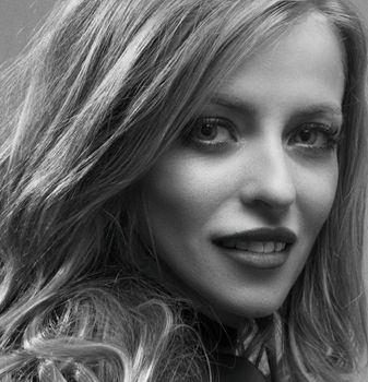 A close-up black and white portrait capturing an elegant woman smiling warmly.