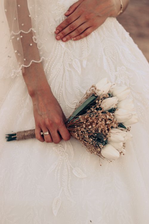 Free Close-up of a bride holding a bouquet of white tulips, showcasing wedding details. Stock Photo