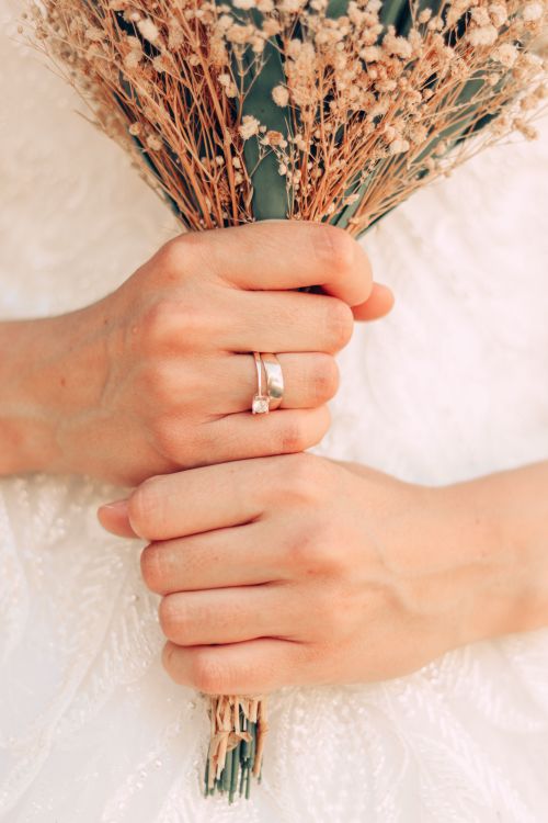 Free Close-up of a bride's hands holding a rustic bouquet, showcasing an elegant wedding ring. Stock Photo