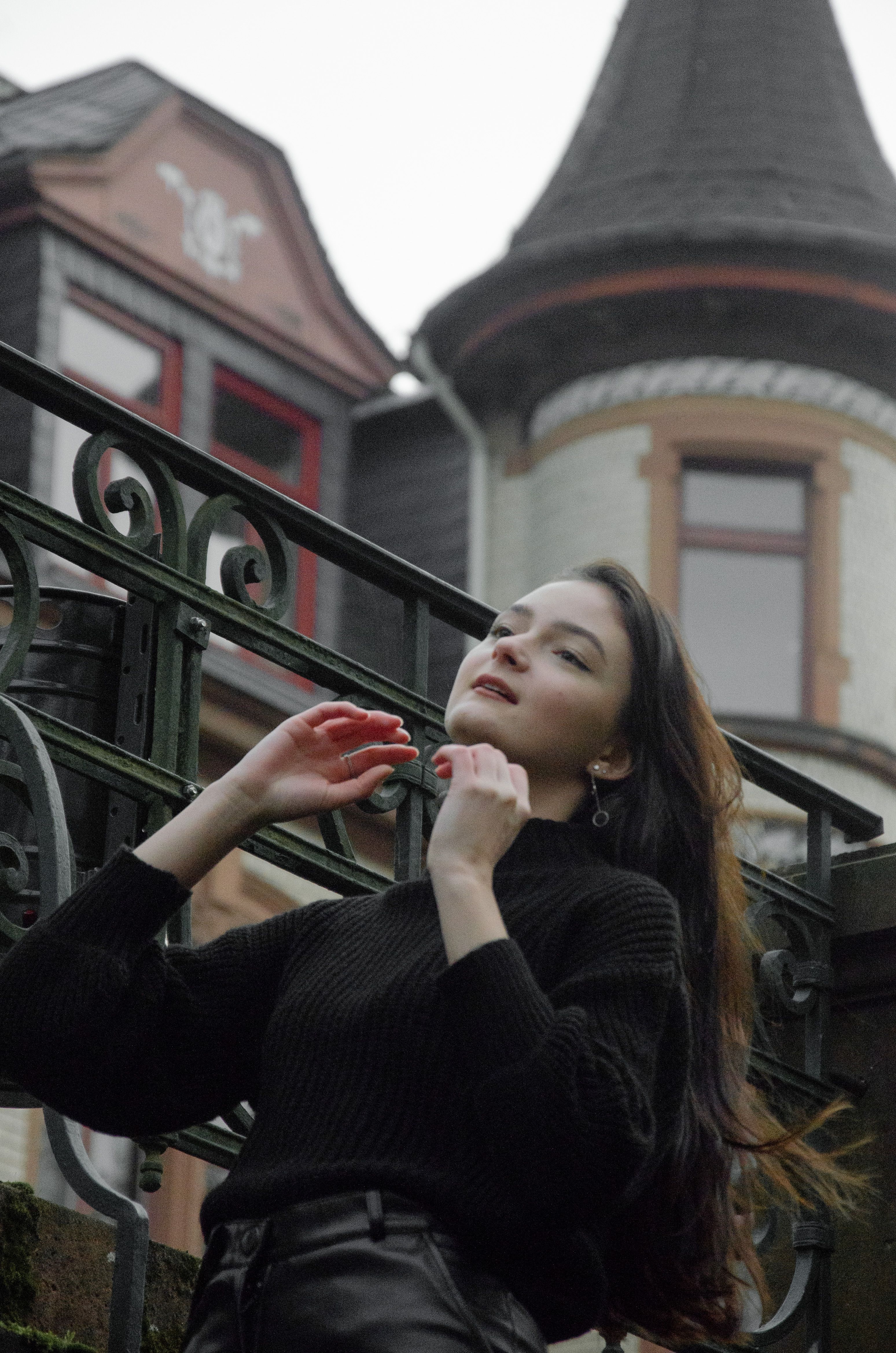 Stylish woman in black fashion poses near an ornate historic building.
