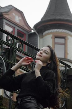 Stylish woman in black fashion poses near an ornate historic building.