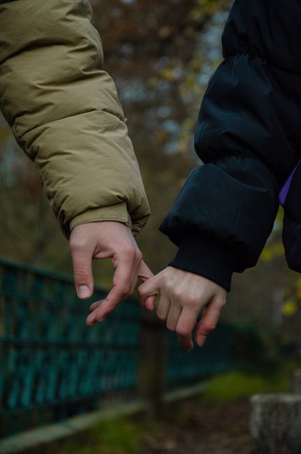 Two people making a pinky promise gesture outdoors, symbolizing trust and connection.
