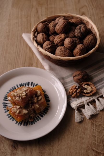 A rustic dessert set with walnuts and a sweet treat on a wooden table, ideal for food photography lovers.