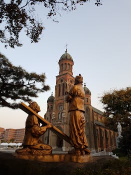Captivating view of Jeondong Cathedral with golden statues, set against a serene sunset in Jeonju, South Korea.