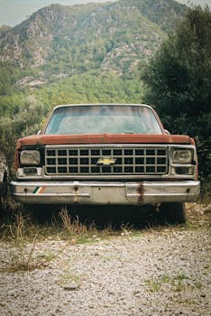 A classic Chevrolet muscle car rests in a serene mountain setting, invoking nostalgia and adventure.