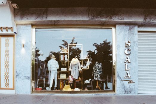 Stylish boutique storefront showcasing elegant winter fashion with reflective display window and Scala signage.