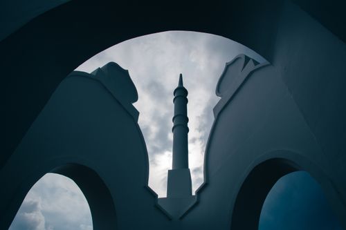 Free Silhouette of a mosque minaret framed by arches against a dramatic overcast sky in Banting, Malaysia. Stock Photo